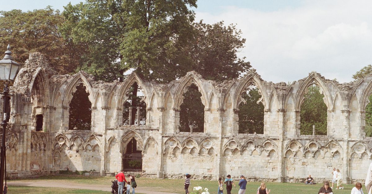 Visitors explore the medieval ruins of St. Mary's Abbey on a sunny day in York, England.